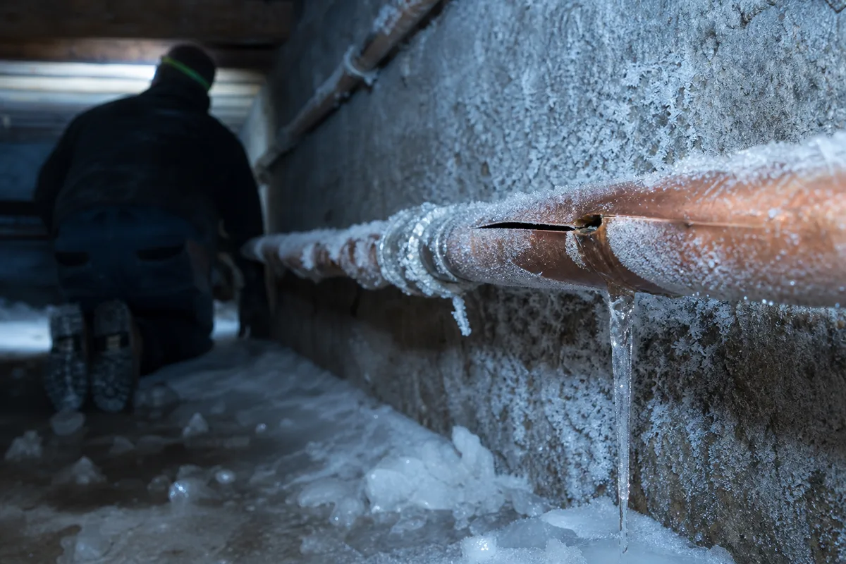 Conduite d&rsquo;eau gelée et éclatée dans un vide sanitaire glacé, lumière technique bleutée